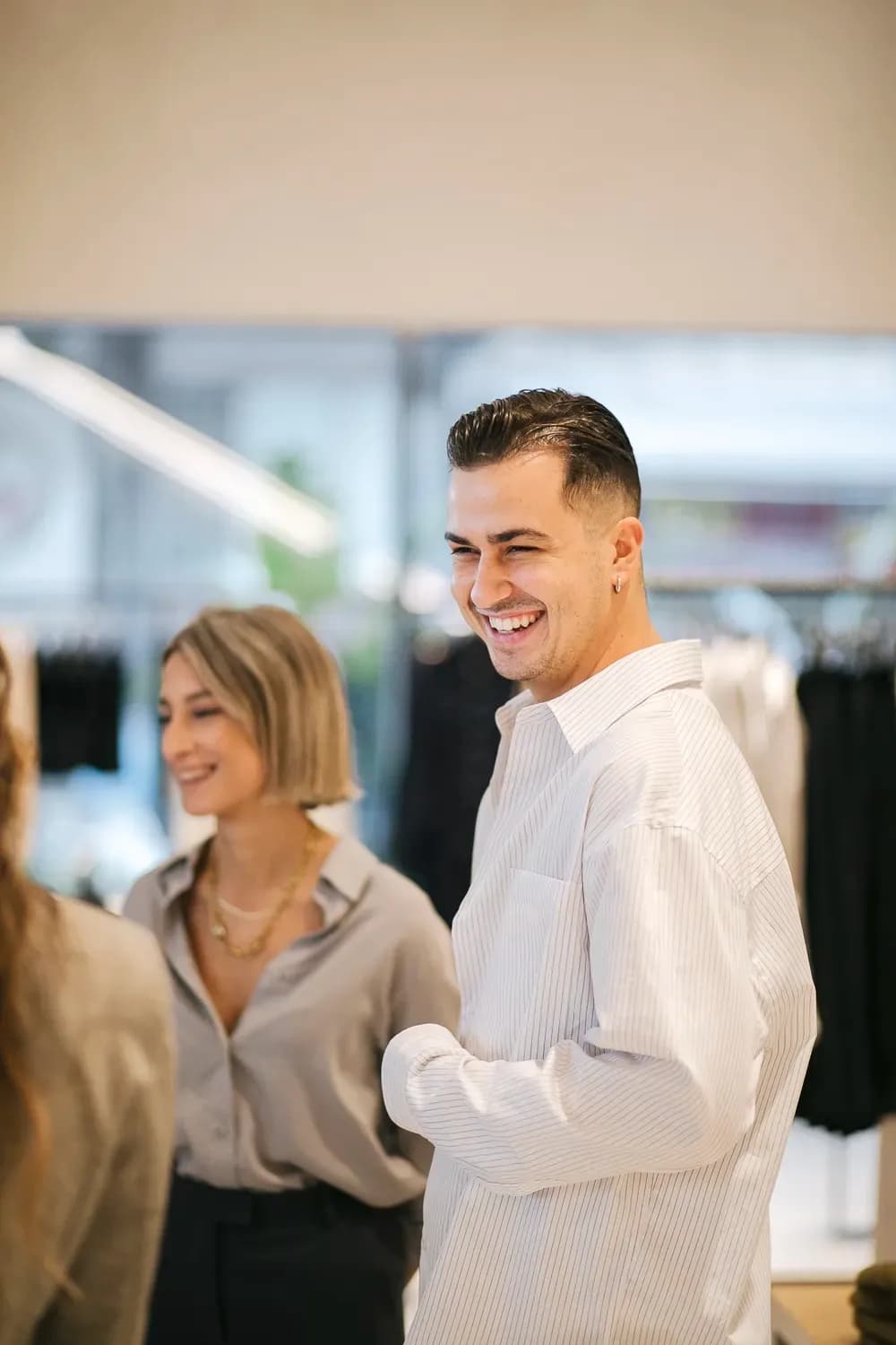 Άνδρας που φοράει ένα ανοιχτόχρωμο ριγέ πουκάμισο με κουμπιά ενώ ψωνίζει σε ένα μοντέρνο κατάστημα ρούχων