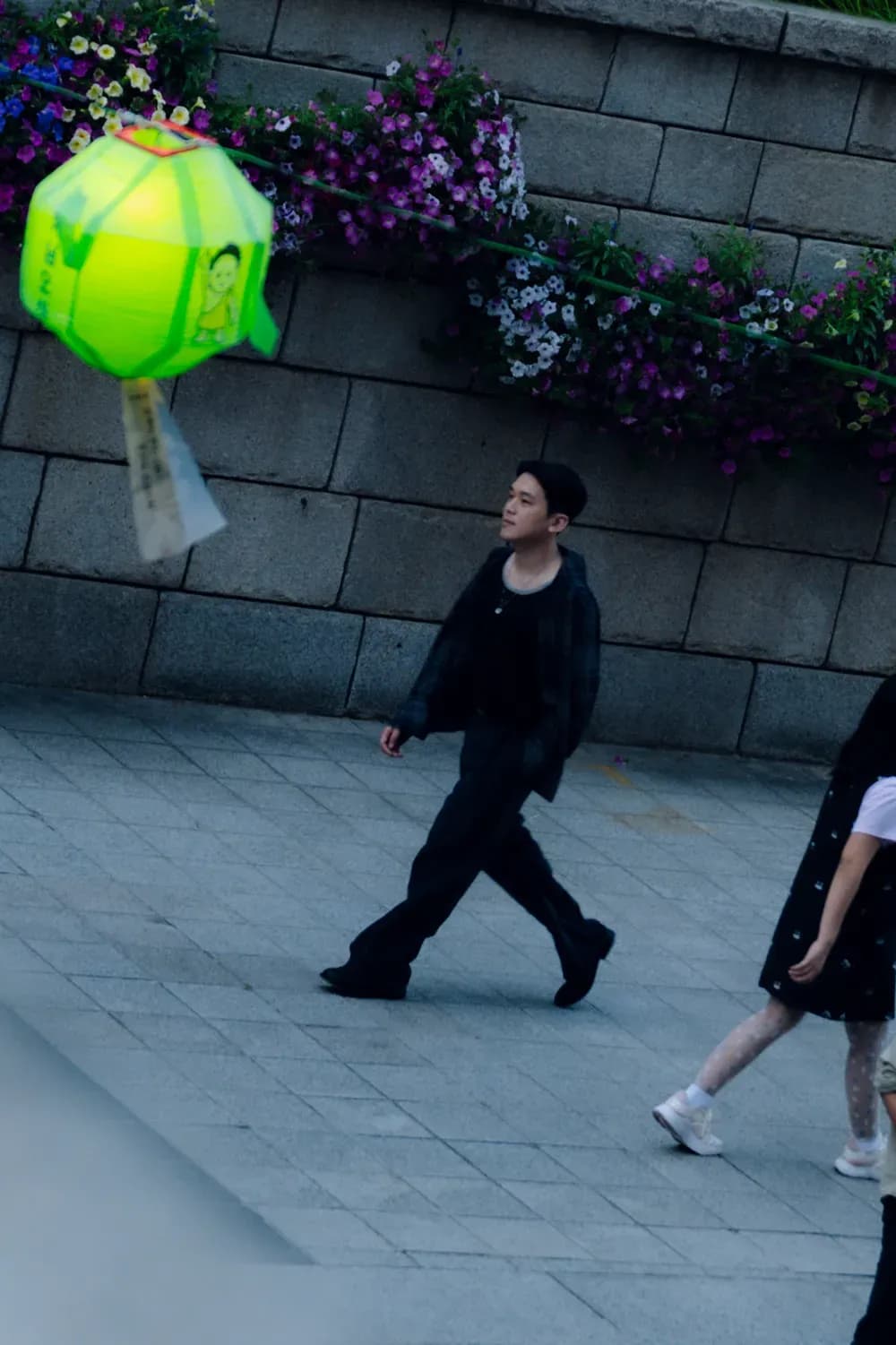 Person wearing a relaxed all-black outfit walking through a city plaza, highlighting contemporary minimalist styling.
