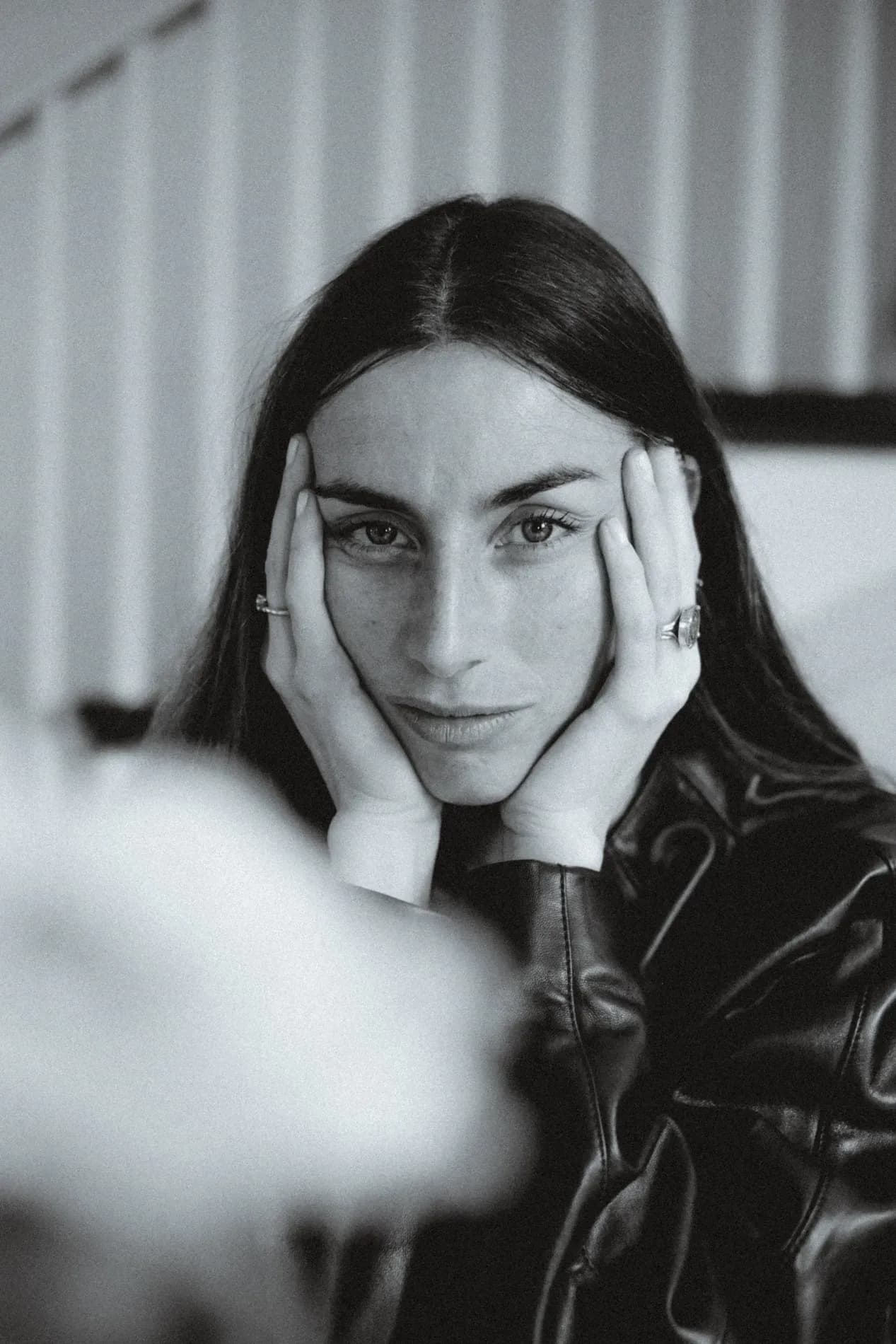 A close-up black-and-white portrait of a woman wearing a leather jacket, highlighting texture, contrast, and a minimal, expressive mood.
